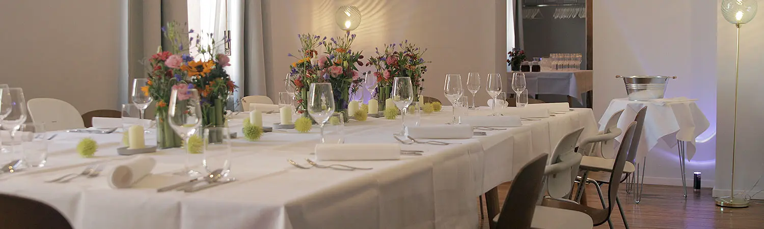 Festlich gedeckter Tisch mit bunten Blumenarrangements und Gläsern