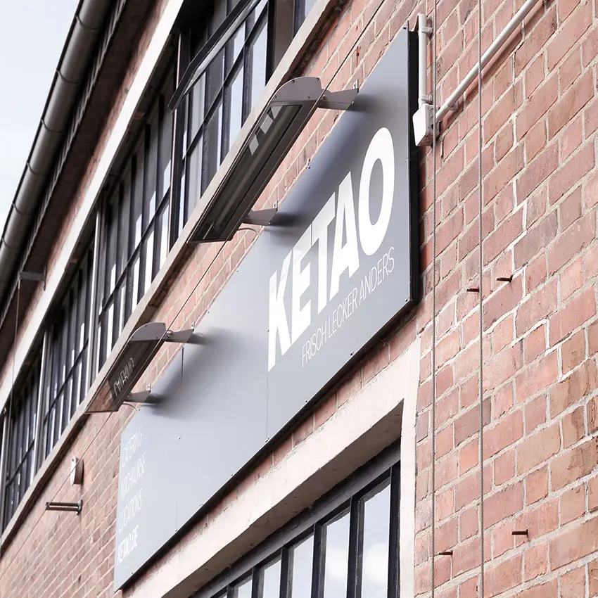 KETAO Gebäudefassade mit Firmenschild an roter Backsteinwand