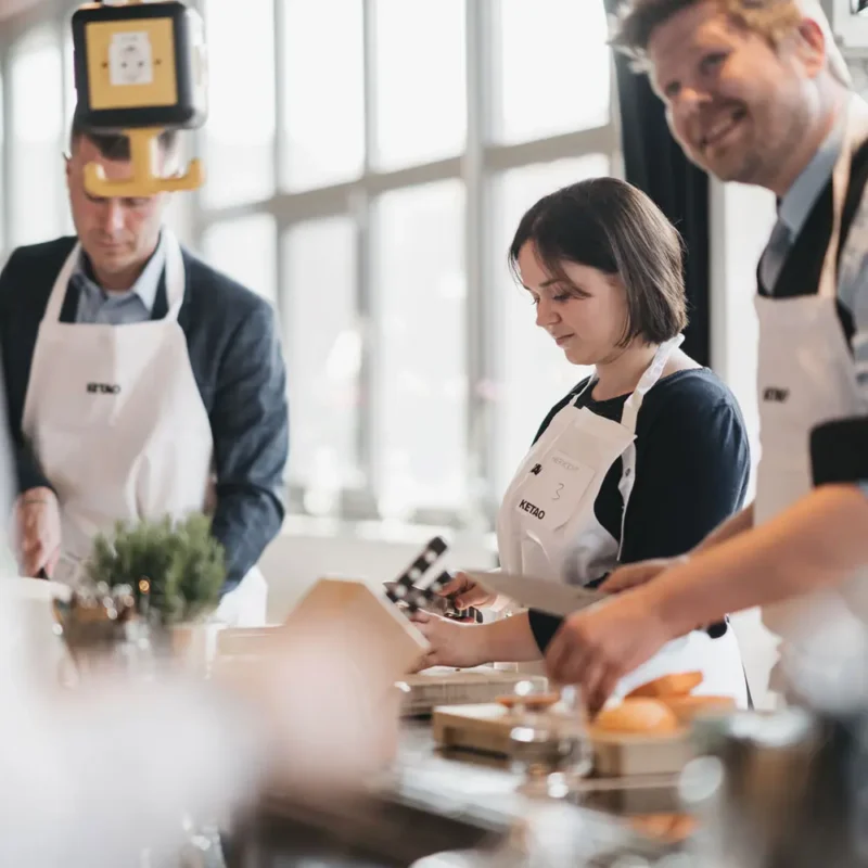 Teilnehmer in Kochschürzen beim gemeinsamen Kochkurs