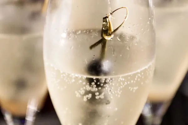 champagner-cocktail-mit-beere Erfrischender Champagner-Cocktail im Glas mit Beere und Sprudel