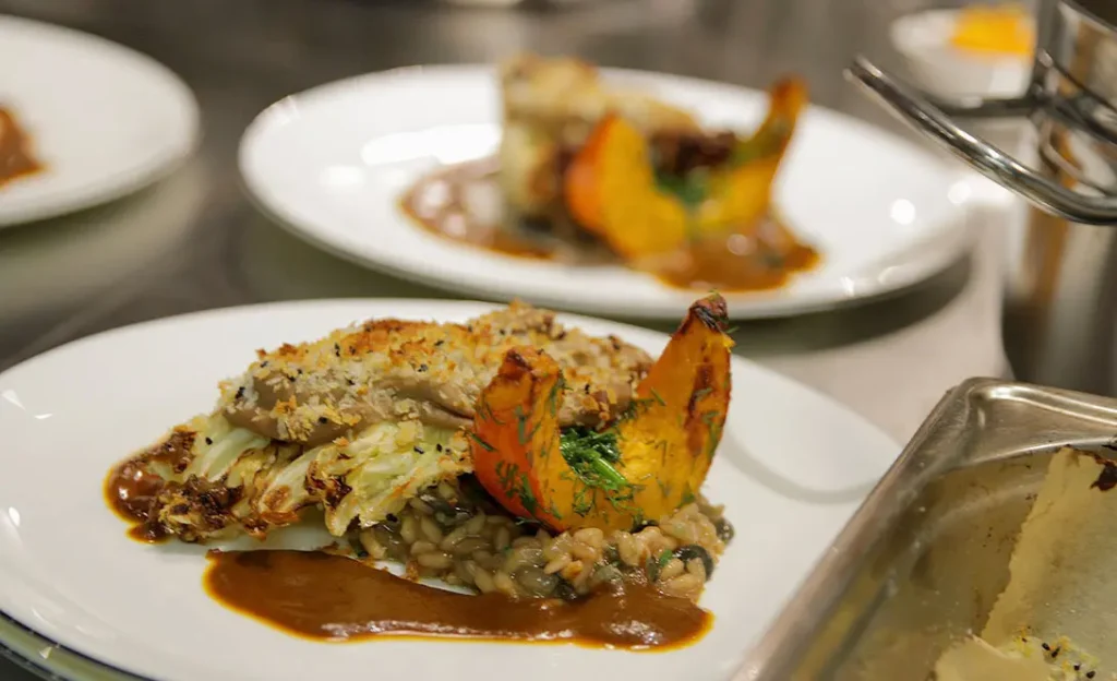 Fein angerichtetes Risotto mit Kürbis und Kraut auf Teller