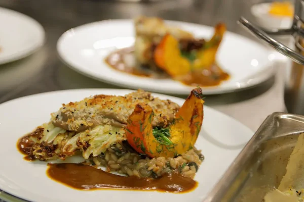 risotto-kuerbis-gourmet Fein angerichtetes Risotto mit Kürbis und Kraut auf Teller