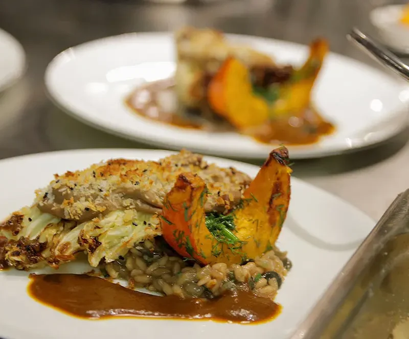 Fein angerichtetes Risotto mit Kürbis und Kraut auf Teller