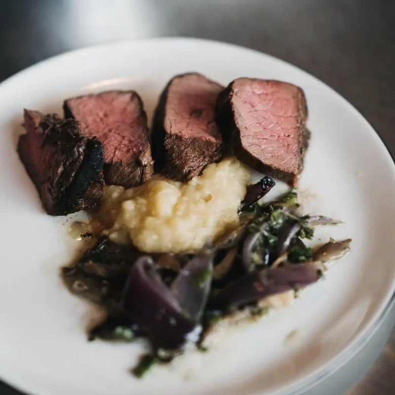 Saftiges Rindfleisch mit Beilage aus Püree und roten Zwiebeln serviert