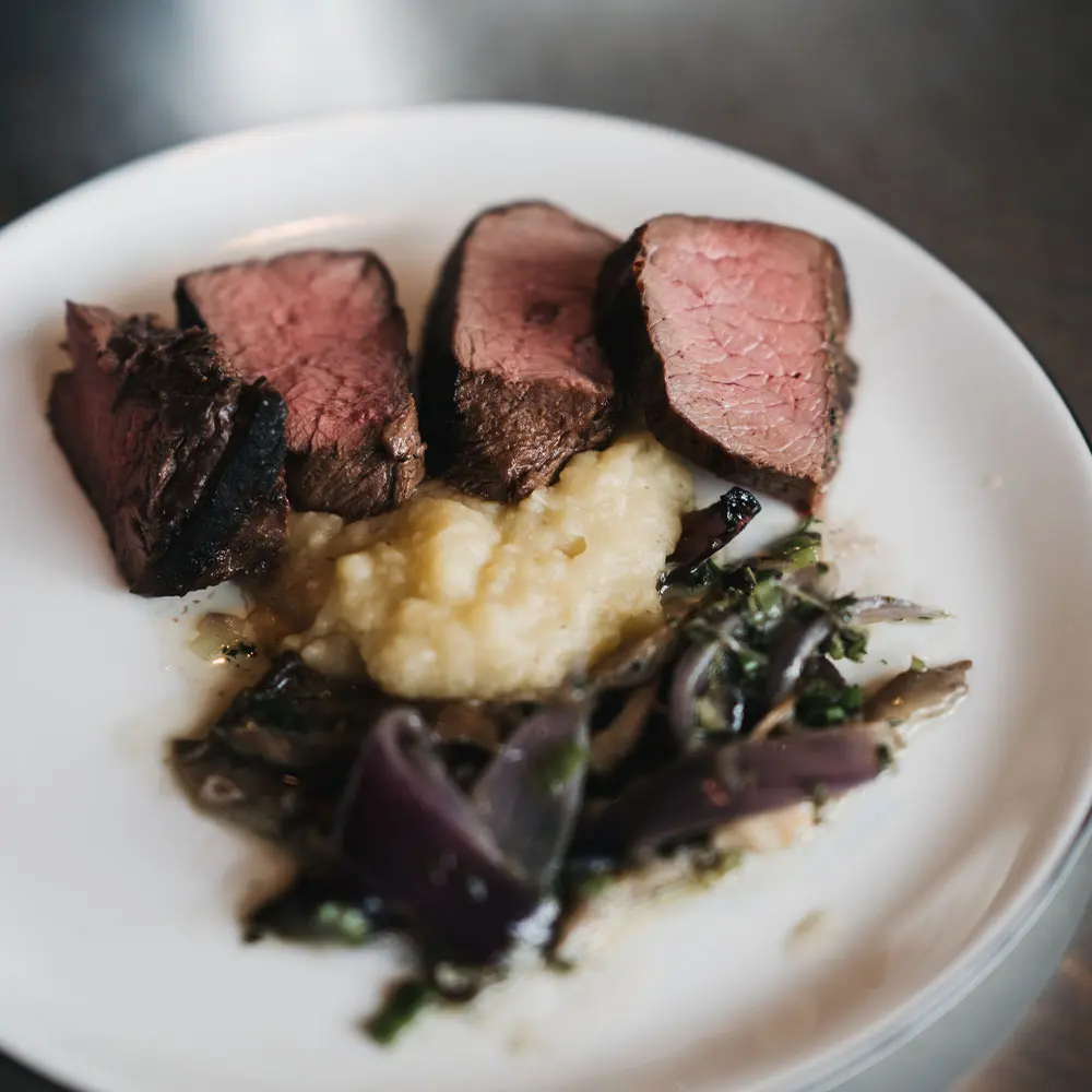 Saftiges Rindfleisch mit Beilage aus Püree und roten Zwiebeln serviert