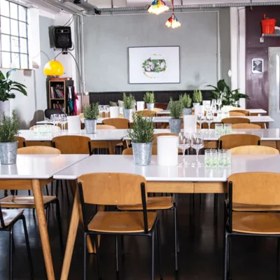 heller-veranstaltungsraum-holztische-kraeuterpflanzen Heller Veranstaltungsraum mit Holztischen, Stühlen und Kräuterpflanzen als Tischdekoration