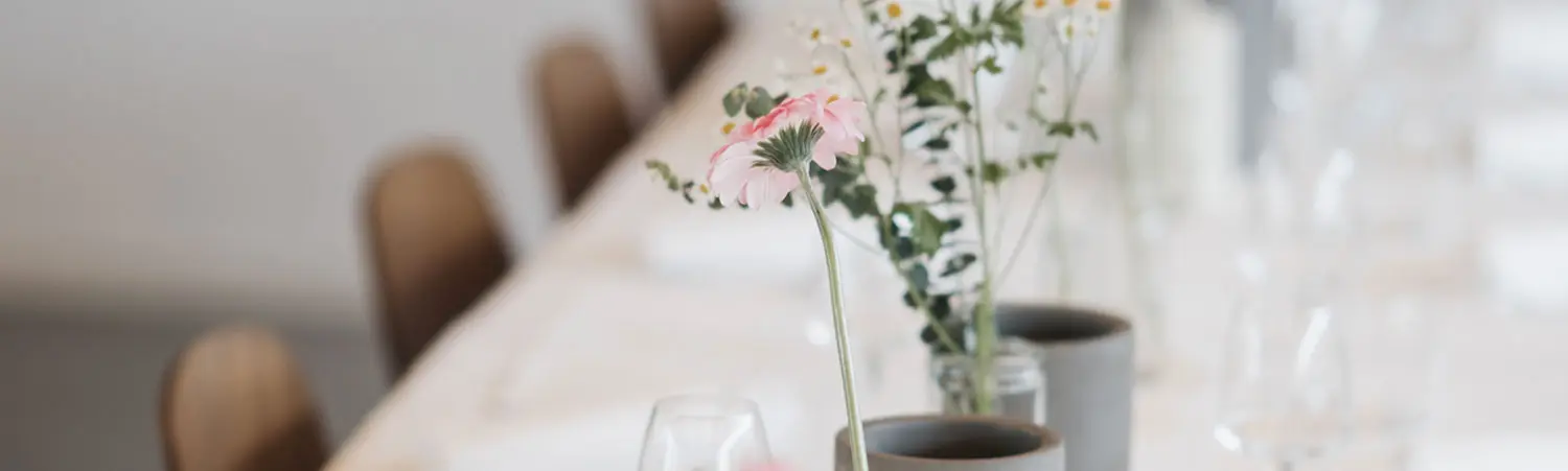 Nahaufnahme einer Tischdekoration mit rosa Blume und Glasvasen