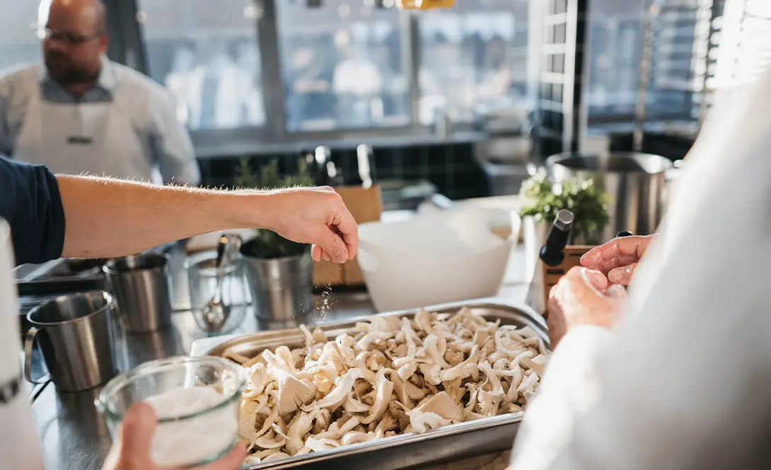 Vorbereitung von frischen Pilzen – Hand streut Salz über Austernpilze
