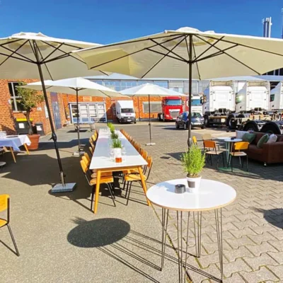 outdoor-eventbereich-tische-sonnenschirme Outdoor-Eventbereich mit langen Tischen und Sonnenschirmen