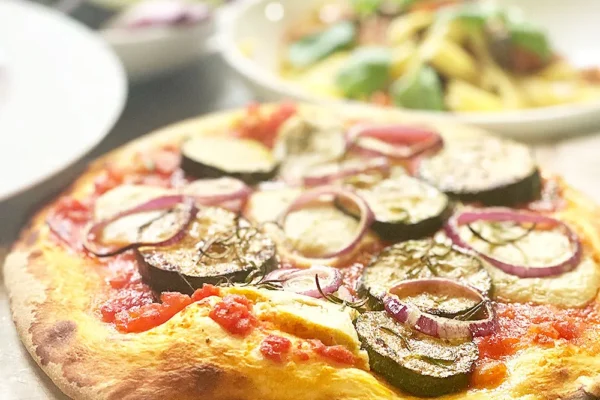 knusprige-pizza-mit-zucchini-und-zwiebeln Knusprige Pizza belegt mit Tomatensauce, Zucchini-Scheiben und roten Zwiebeln