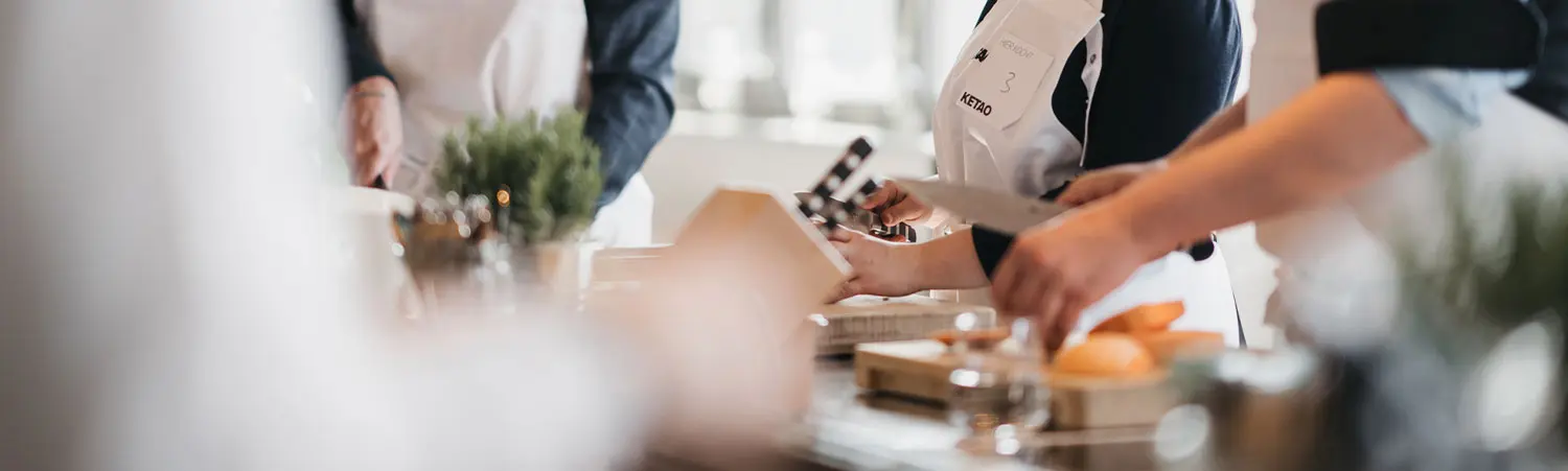 Nahaufnahme von Händen beim Schneiden von Zutaten in moderner Küche