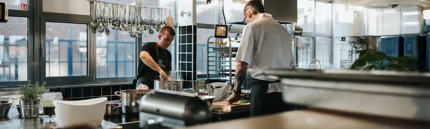 Köche bei der Zubereitung von Speisen in moderner Profiküche