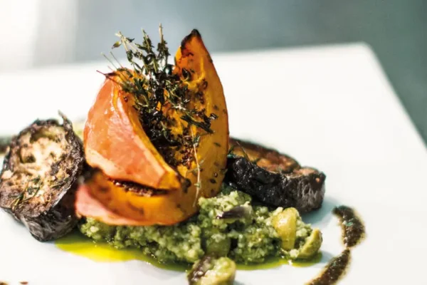 kuerbis-tyhmian-sauce Fein angerichtetes Kürbisgericht mit Kräutern und Sauce