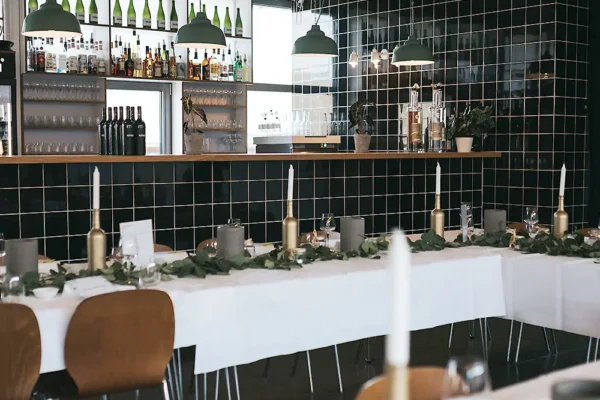 Moderne Eventlocation mit Bar, Weinflaschen und eleganter Tischdekoration