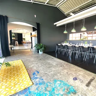 eventlocation-industrial-style Eventlocation mit langen gedeckten Tischen, schwarzen Wänden und buntem Betonboden