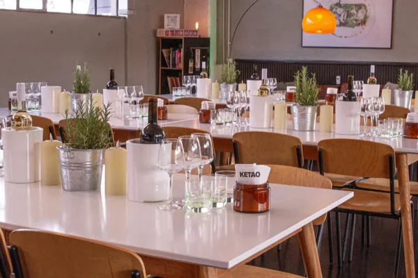 Eingedeckte Tische mit Wein, Gläsern und Kräuterdeko im modernen Eventraum