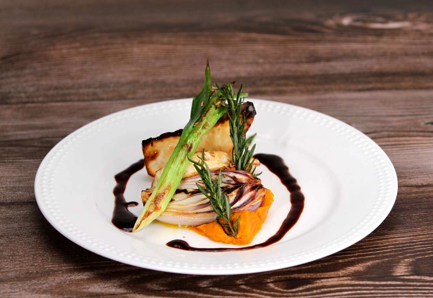 IMG_9033_web - KETAO | FRISCH. LECKER. ANDERS. Elegant plated dish: roasted vegetables (asparagus/green onion) stacked over a carrot-orange purée with a rosemary sprig and balsamic glaze drizzle