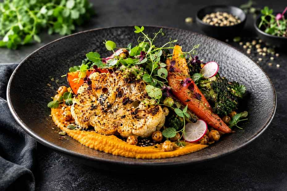 ketao_vegan_04 - KETAO | FRISCH. LECKER. ANDERS. Roasted cauliflower steak with carrots, broccoli, chickpeas, radishes and microgreens on a black plate